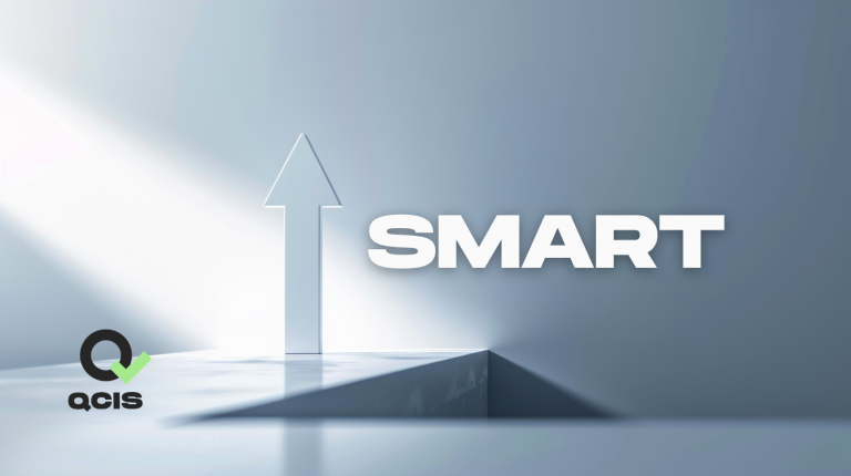 Grafika 3D z dużą strzałką skierowaną do góry i napisem „SMART” po prawej stronie. W lewym dolnym rogu widoczne logo QCIS z zielonym znakiem kontrolnym.